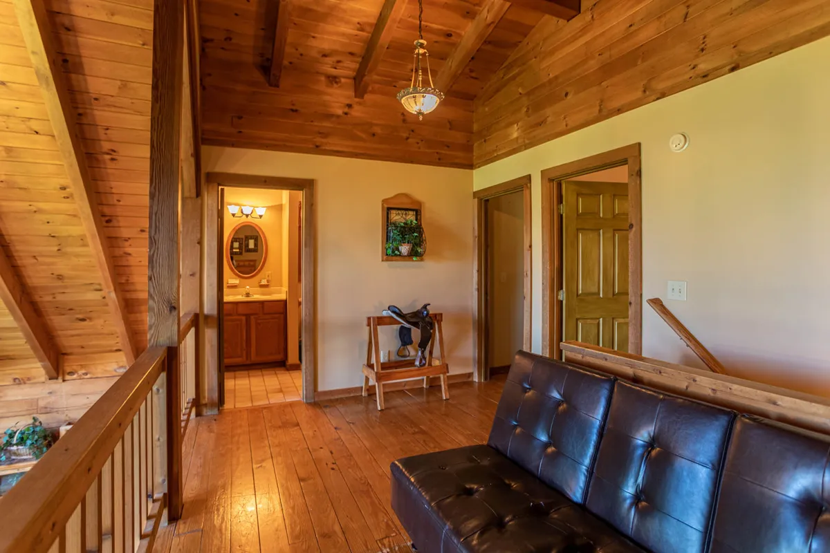 A welcoming living space with a comfortable sofa, exposed wooden beams, inviting lighting, and visible doorways leading to other parts of the cabin. The setup suggests a space for gathering, relaxing, and planning the next adventure, with hints of the cabin's rustic charm and mountain location.