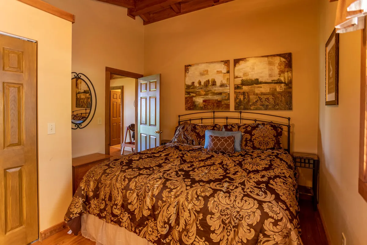 A cozy bedroom with an ornate bed covered in plush bedding, tastefully decorated with art and a decorative mirror. The setting is inviting, ideal for quiet moments of relaxation, reading, or taking a restorative break during a busy workday.