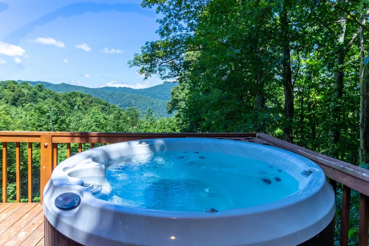 An expansive deck set against sweeping mountain backdrops, featuring a bubbling hot tub and space for relaxing or entertaining. The deck's position allows for sunset viewing, stargazing, and enjoying the fresh mountain air in style.
