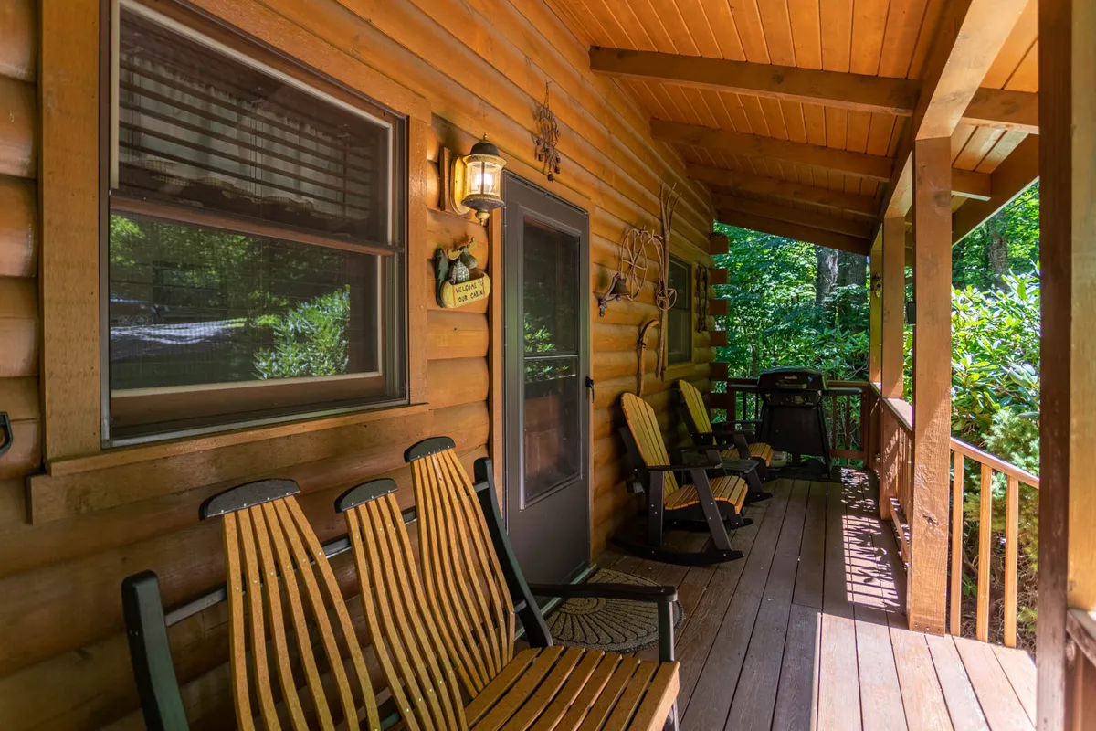 The cozy front porch features classic wooden rocking chairs, a welcoming lantern, and is surrounded by verdant greenery. This inviting space is ideal for relaxing with friends, reading, or simply soaking in the peaceful mountain atmosphere before or after a day filled with local activities.