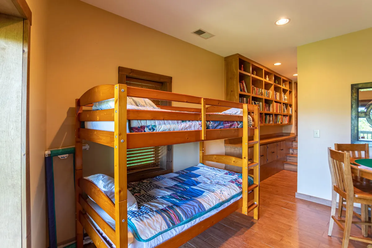A family-friendly bunk room offering bunk beds, a bookshelf, and a small table with chairs. The space is designed for kids and teens to sleep, read, or gather together, fostering both connection and independence within the home.