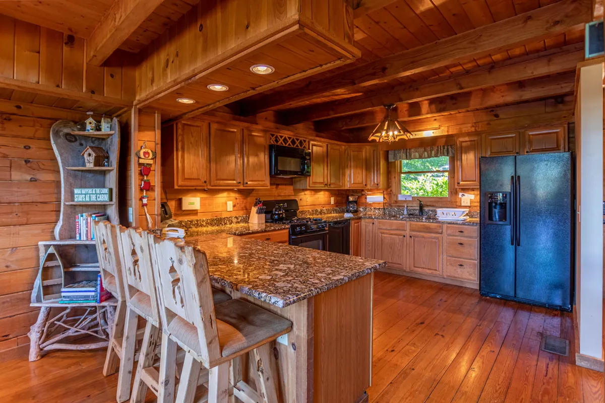 A well-appointed kitchen with a gleaming granite countertop, wooden cabinetry, and comfortable bar stools, suggesting a space for both meal preparation and casual conversation. The design encourages informal gatherings and can double as an alternative workspace for remote tasks.